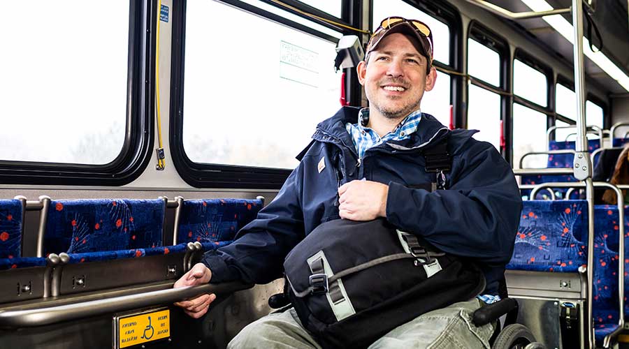 Man in wheelchair smiling while riding a bus