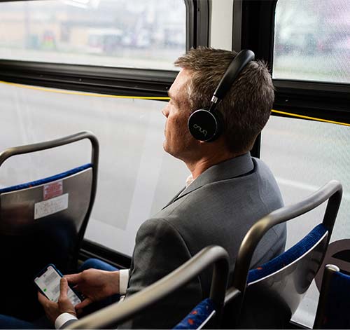 Business man riding the bus listening to music with headphones from his cell phone