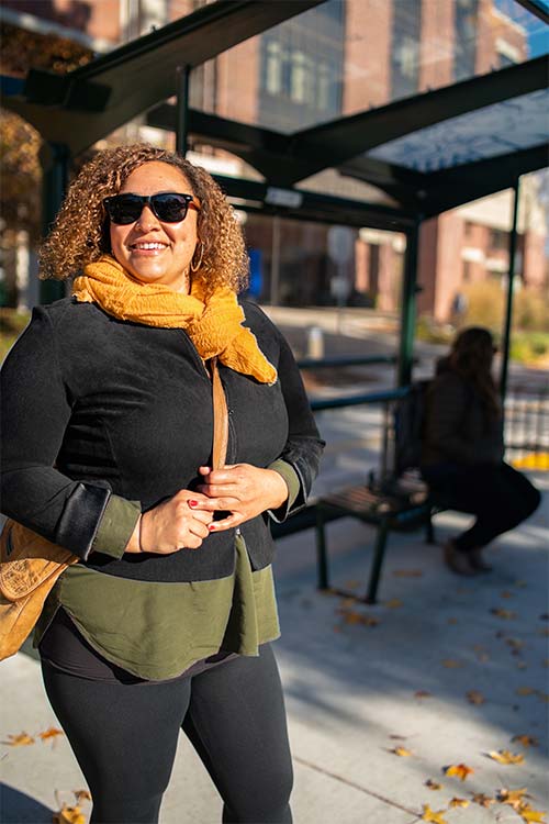 Woman wearing sunglasses waiting for the bus outside