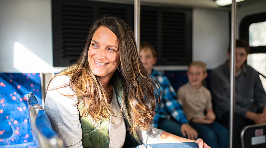 Woman riding a bus and smiling while looking out the bus window