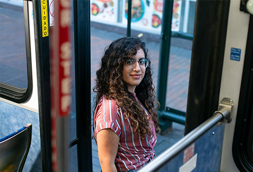 Woman wearing glasses and exiting the bus while looking back